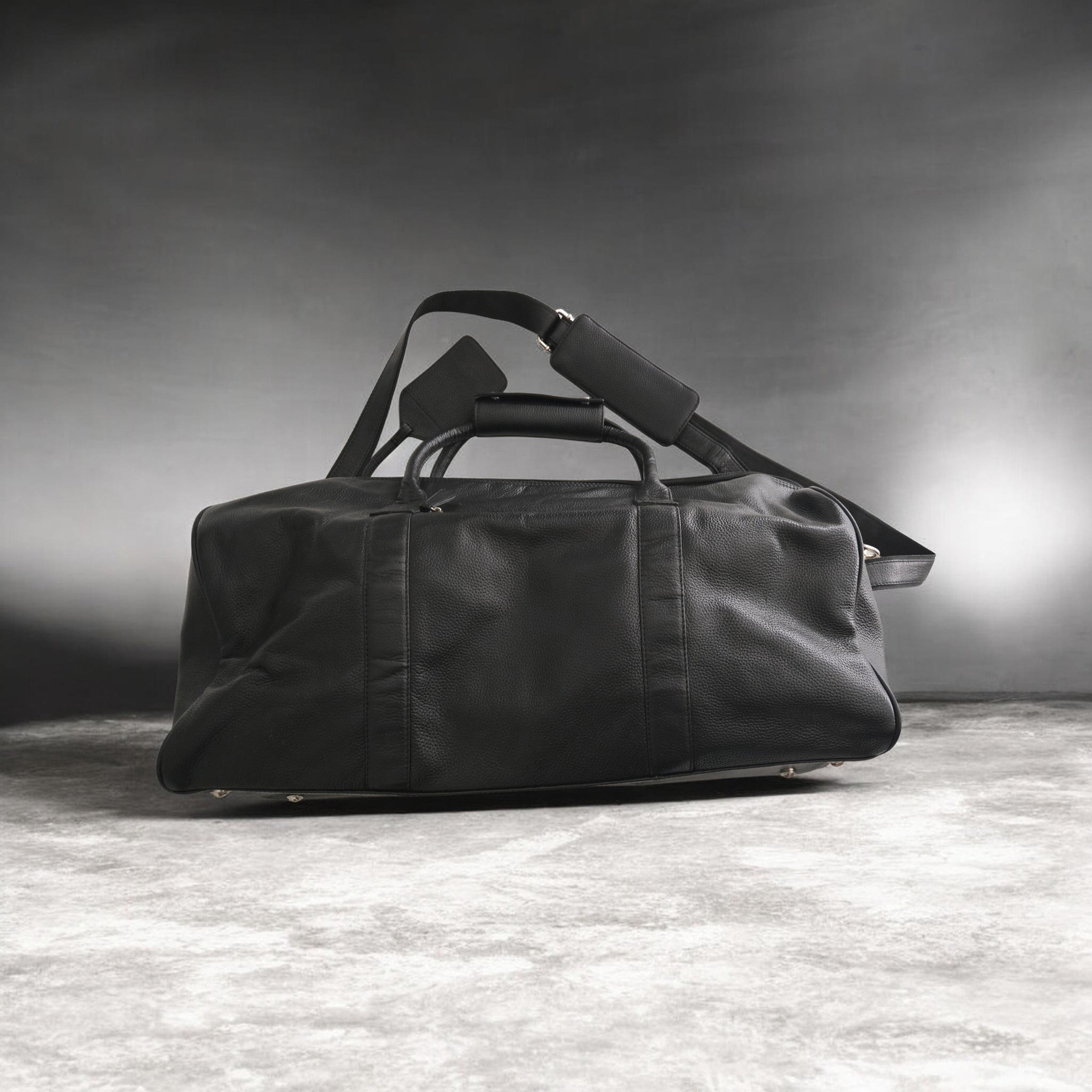 Black duffel bag on a textured surface with a dark background