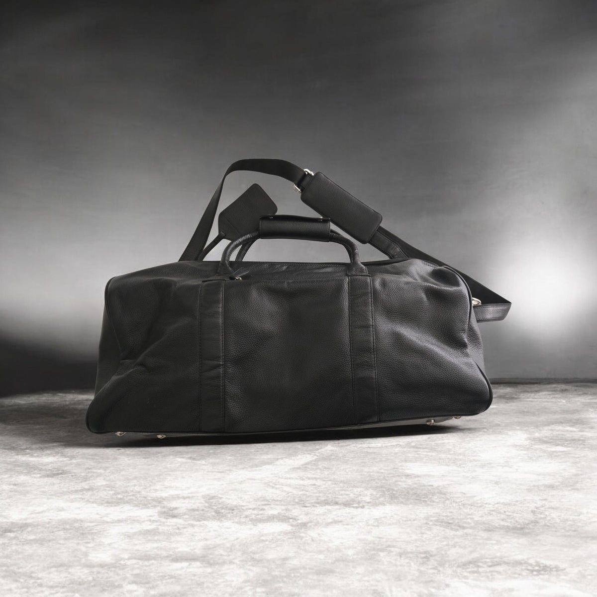 Black duffel bag on a textured surface with a dark background